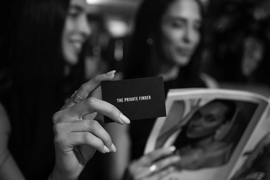 Une main tient une carte noire portant le nom The Private Finder.